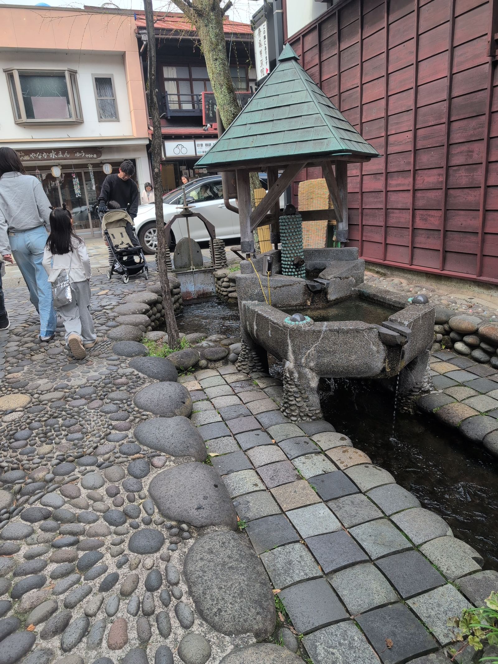 A traditional building and small shrine beside a clear water canal in Gujo Hachiman
