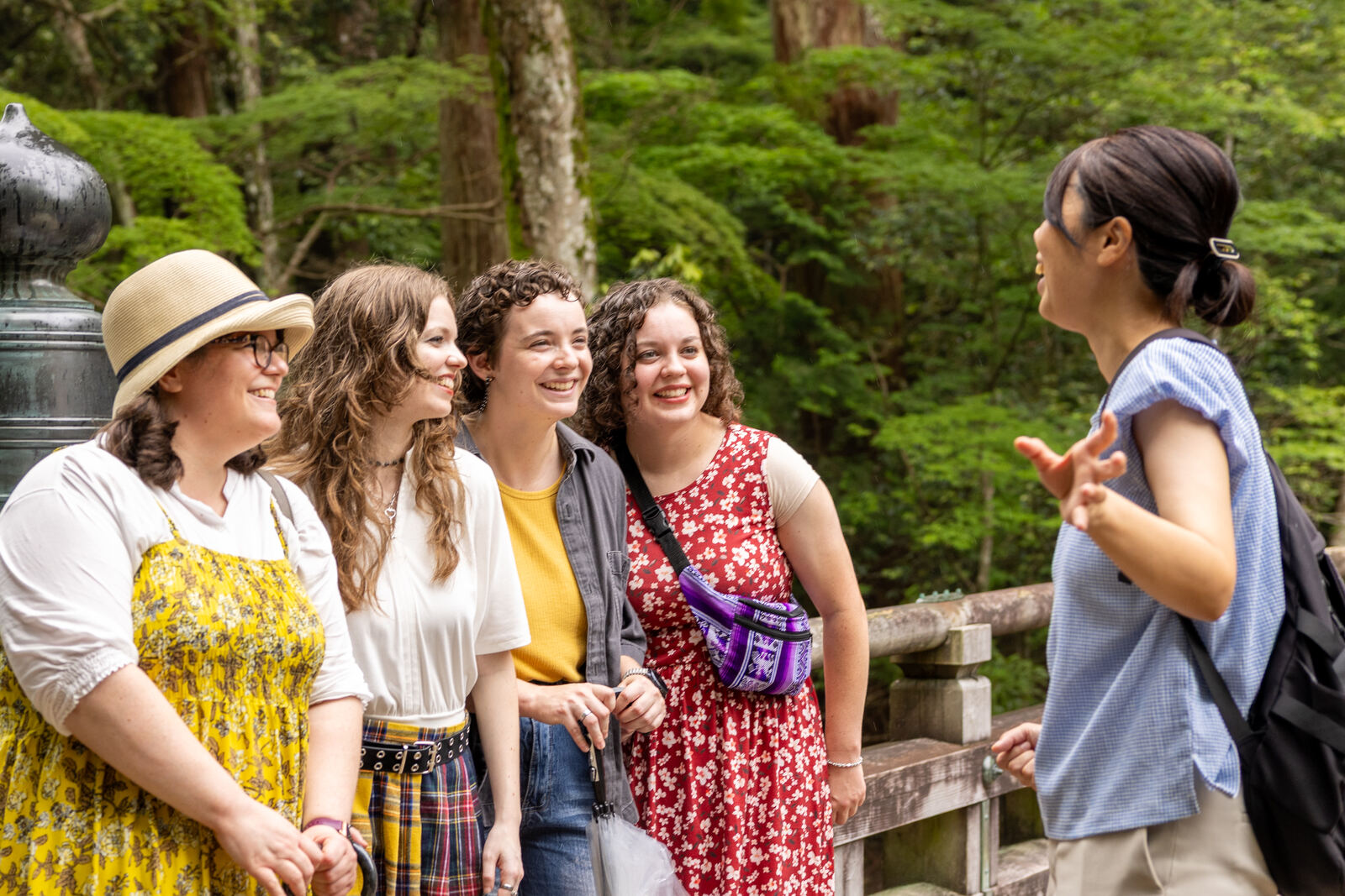 Misae and guests talking beside a stone lantern in the forest