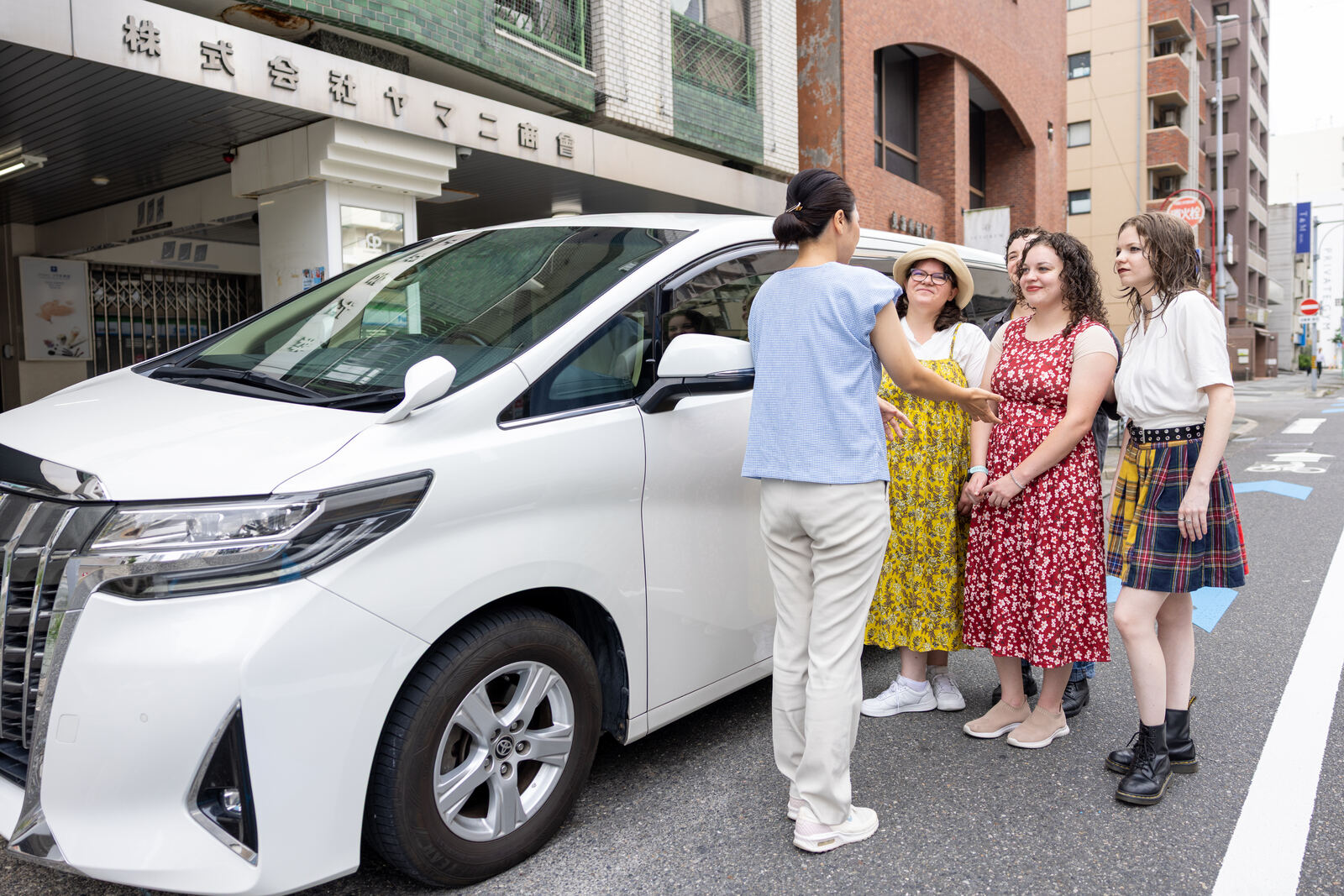 Misae greeting guests beside the pickup vehicle in Nagoya