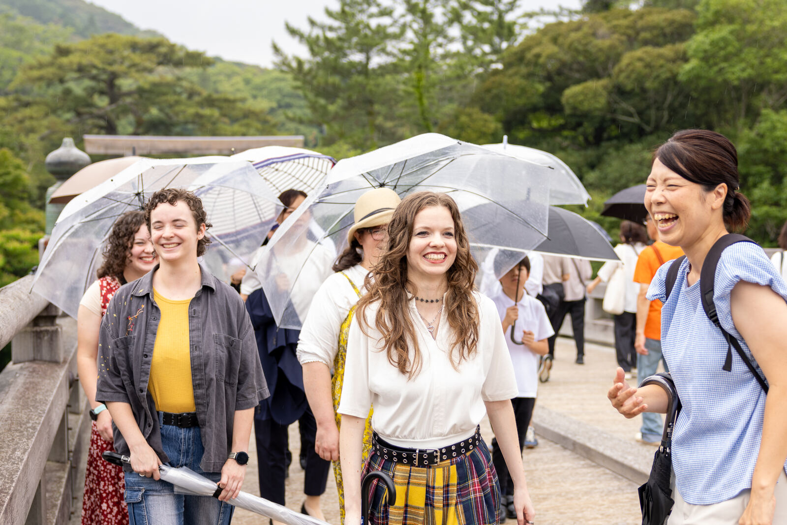 Guests walking across the bridge together under umbrellas