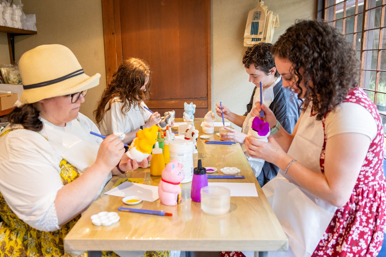Guests painting their own maneki-neko lucky cats at a table
